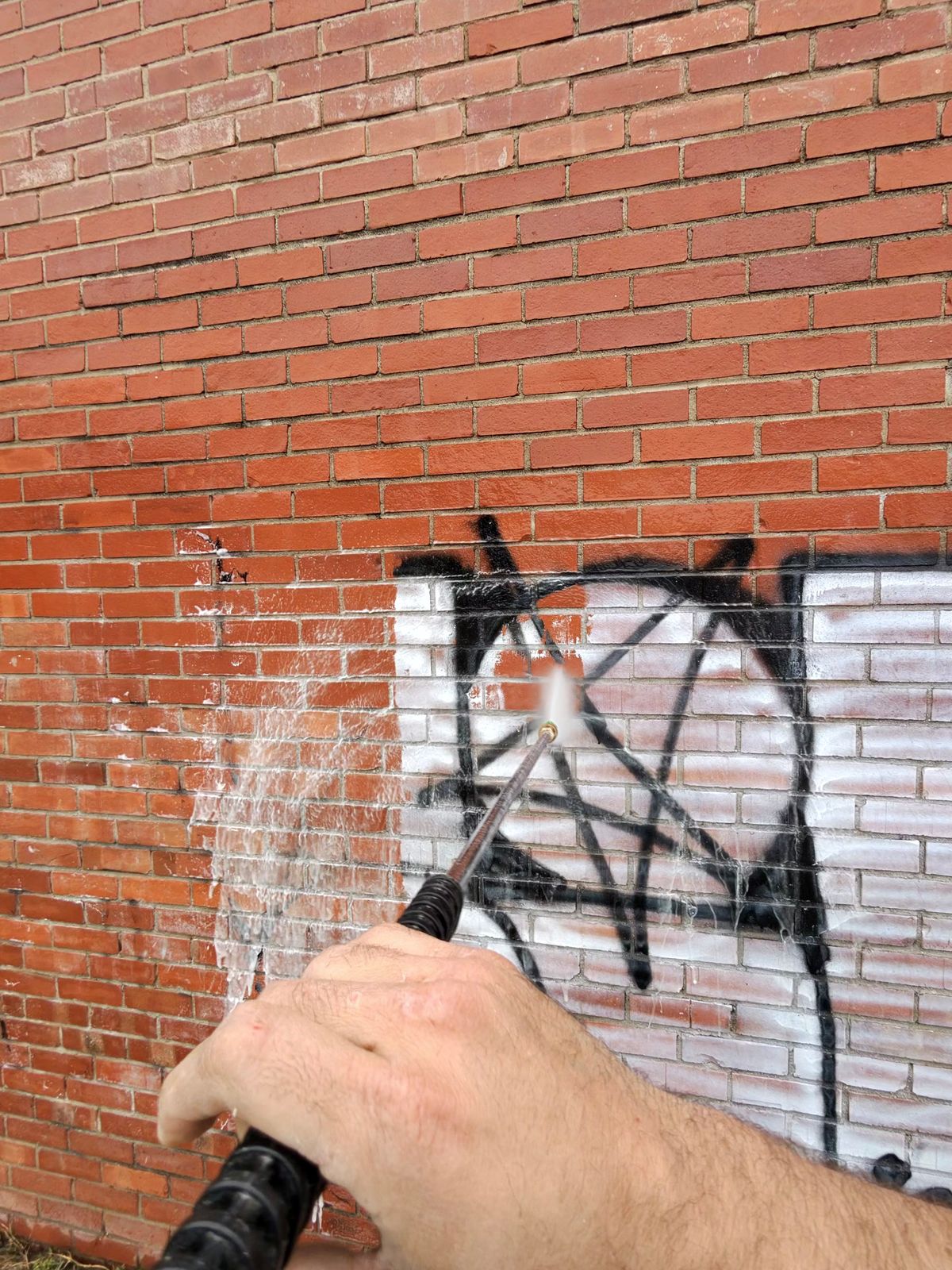 Removing silver graffiti from a red brick wall in Wichita, KS