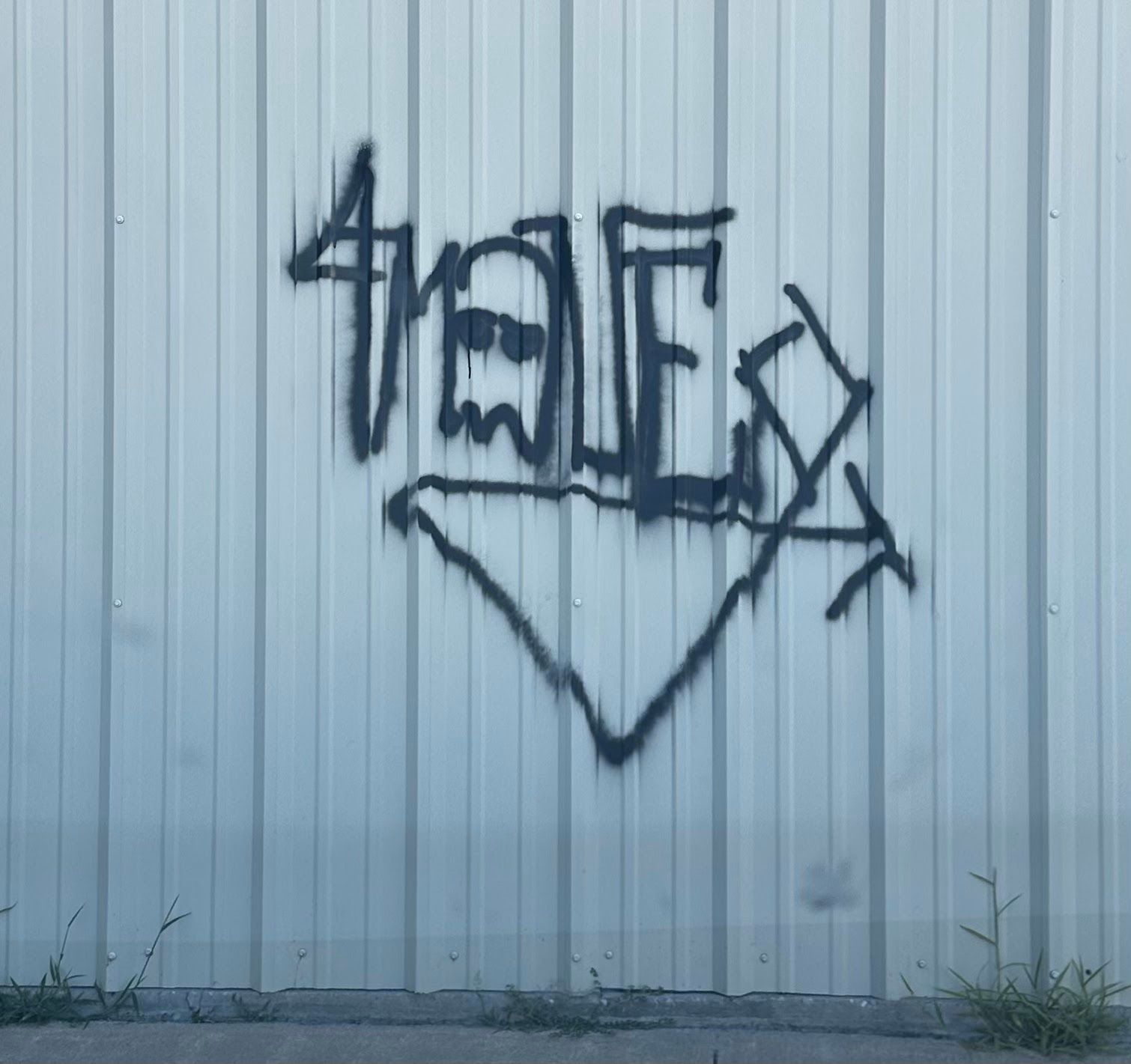 Black graffiti on metal siding before removal, Wichita, KS