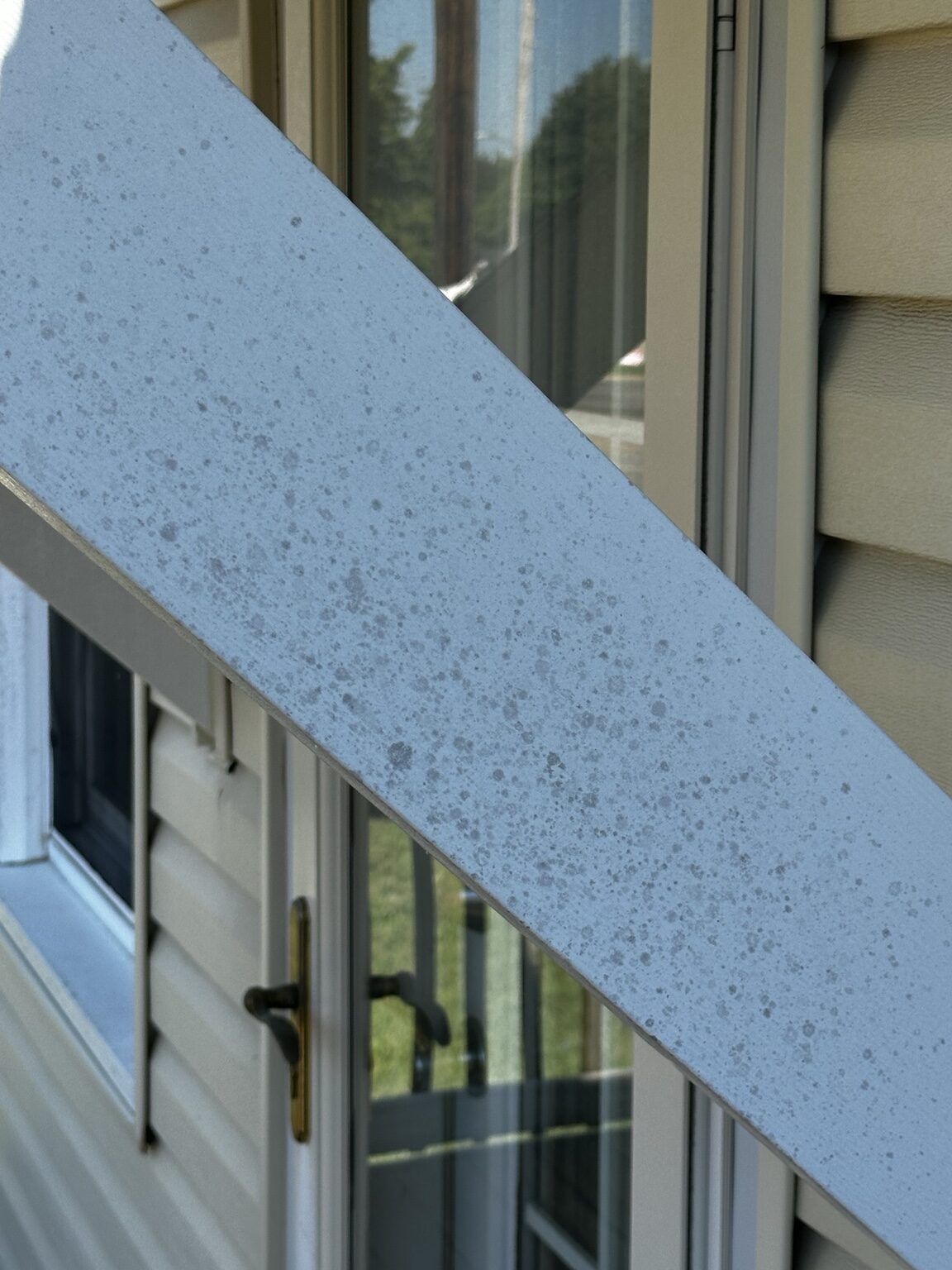 Organic growth on white porch trim before house washing in El Dorado, Kansas