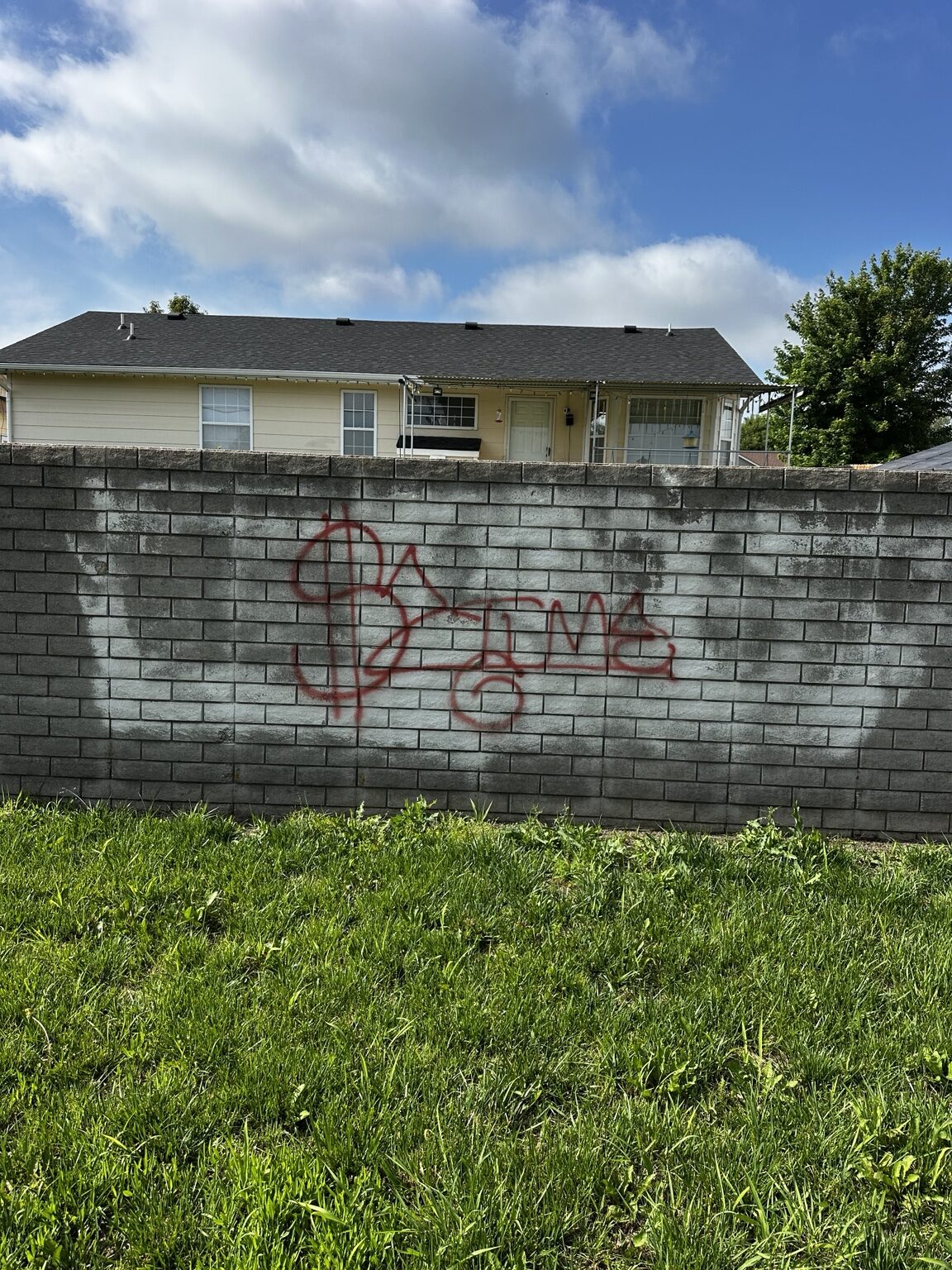 Red graffiti on a concrete block wall before removal