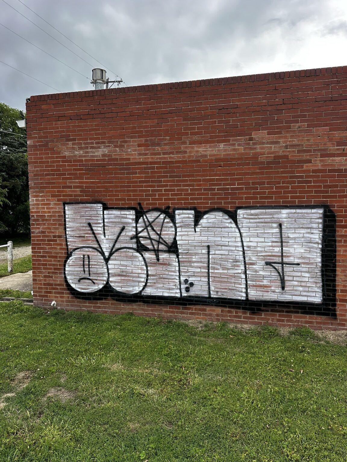 Large white and black graffiti tag on a brick commercial wall in Wichita